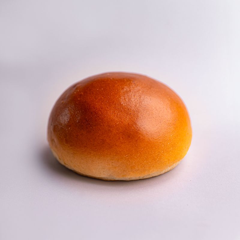 A single plain, glossy golden burger bun