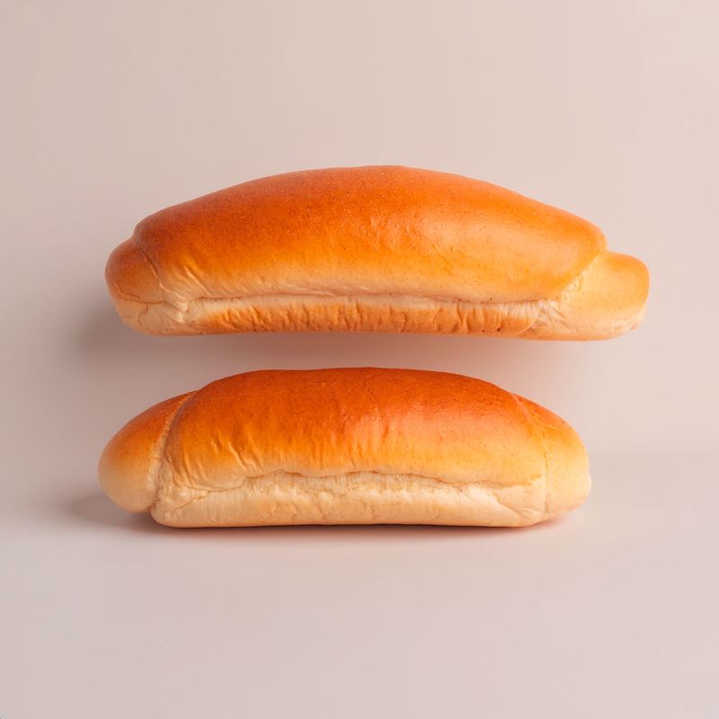 Two golden hot dog buns, one above the other